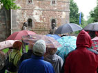 Die Hanauer Touristen vor den zwei Statuen im Regen unter  Schirmen
