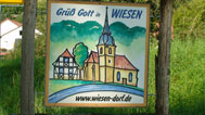 Schild am Ortseingang in Wiesen: Grüß Gott in Wiesen mit Bild und internetadresse www.wiesen-dorf.de