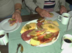 Blick auf Frühstückstisch, Teller mit belegten Brötchen, Tassen mit Kaffee