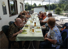 Pitschedabber an einem langen Tisch auf der Terrasse des Anglerheims, vorne rechts Ingrid M., links Edgar und Regina