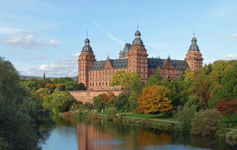 Blick auf das Schloss von der anderen Mainseite. Man sietht 2 Seiten, drei Ecktürme und dahinter den Berfried