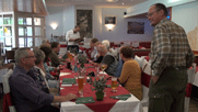 die Pitschedabber sitzen an einem langen Tisch im Restaurant, vorne stehand Achim