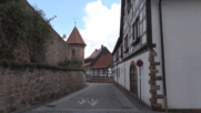 Straße in Dörrenbach, rechts Fachwerk haus, links Mauer un Wehrturm der Wehrkirche.