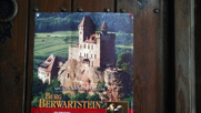 Plakat mit der Burg oben  auf dem Felsen