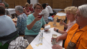 im Muskatellerhof am Tisch Ingrid K., Josef, Silvia.Ingrid hebt das Glas mit rotem Wein, die anderen trinken Schorle