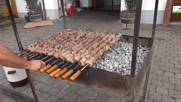 ca 15 etwa 1,5m lange Spieße mit dicken Fleischbrocken bestückt, liegen nebeneinander auf dem Holzkohlengrill