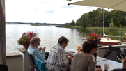 Blick von der Terrasse auf den See, im Vordergrund Gaby, Ingrid, Sylvia von hinten, beschäftigt mit ihren elektronischen Geräten.