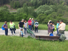 die Gruppe macht Pause bei der Bank, Achim gießt Sekt aus,  links Sandra mit Ehemann,  Tochter und Kinderwagen