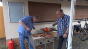 Andreas und Rainer am Grill, auf dem bereits das Grillgut liegt