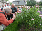 im Rosengarten, Klaus riecht an einer Rose,  dahinter Alwin, Udo, Reingard