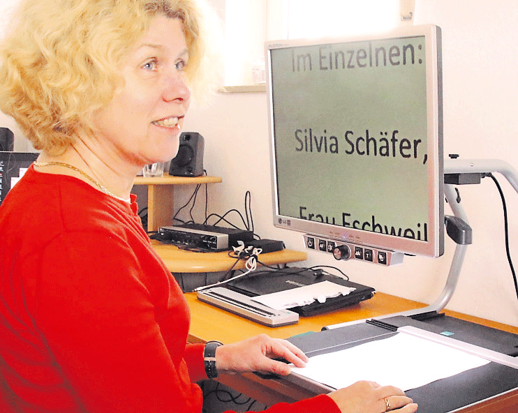Silvia Sch&auml;fer vor der elektronischen Lupe und Braillezeile vor dem Computer