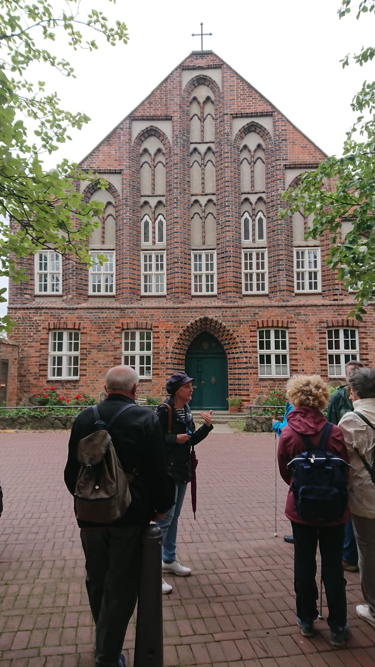 Die Reisegruppe steht mit der Stadf�hrerin vor einem alten Geb�ude. Sie scheint den Anwesenden etwas zu erkl�ren.